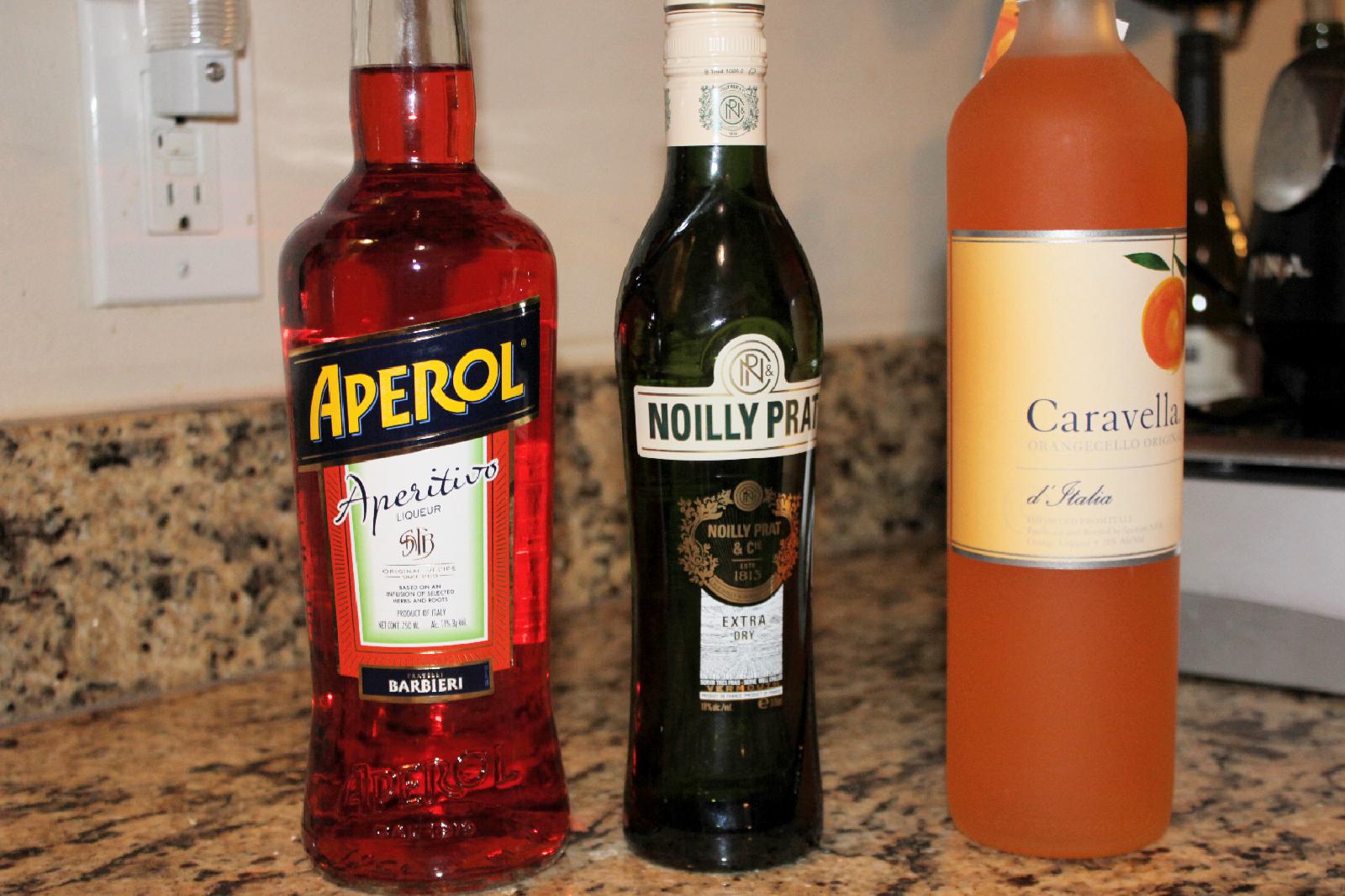 Bottles of Aperol, vermouth, and orangecello on a counter