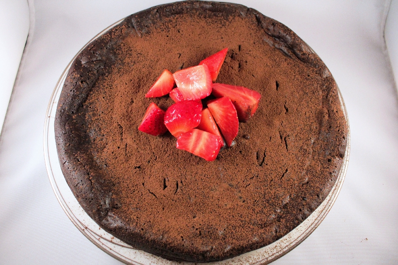 Flourless dark chocolate cake topped with macerated strawberries