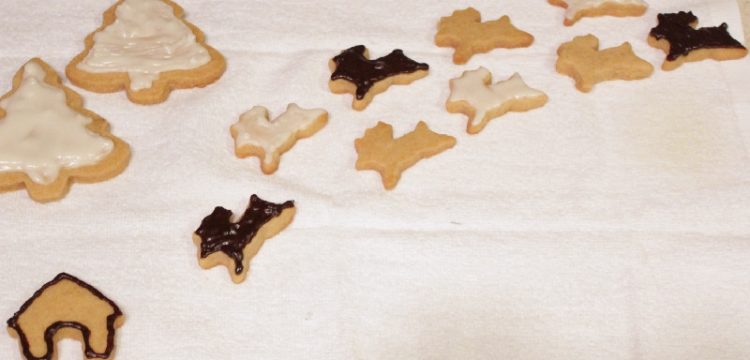 Iced peanut butter cutout cookies in the shapes of reindeer and Christmas trees