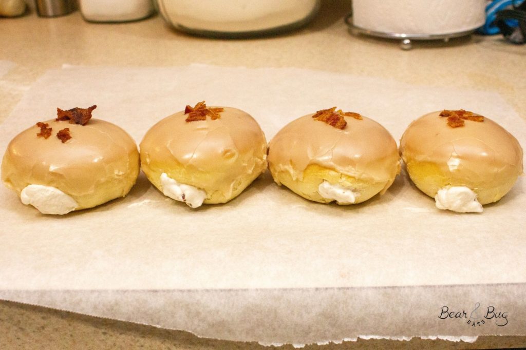 4 maple bacon cream baked donuts in a line on a countertop