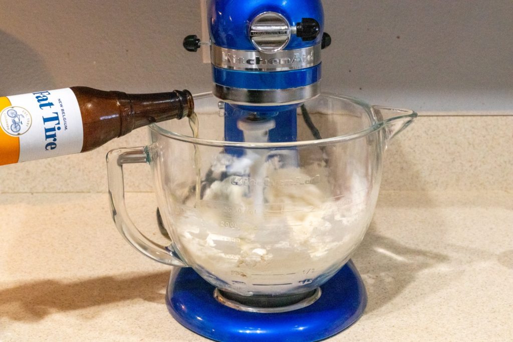 Stand mixer with dough, beer being poured in