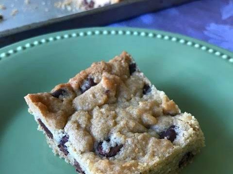 Chocolate chip cookie bar on a plate with pan in background