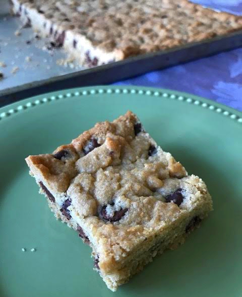 Chocolate chip cookie bar on a plate with pan in background