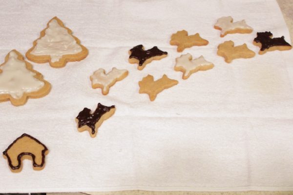 Iced peanut butter cutout cookies in the shapes of reindeer and Christmas trees